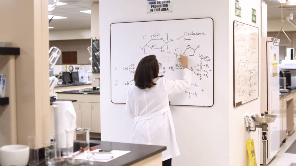Un scientifique écrit sur un tableau blanc